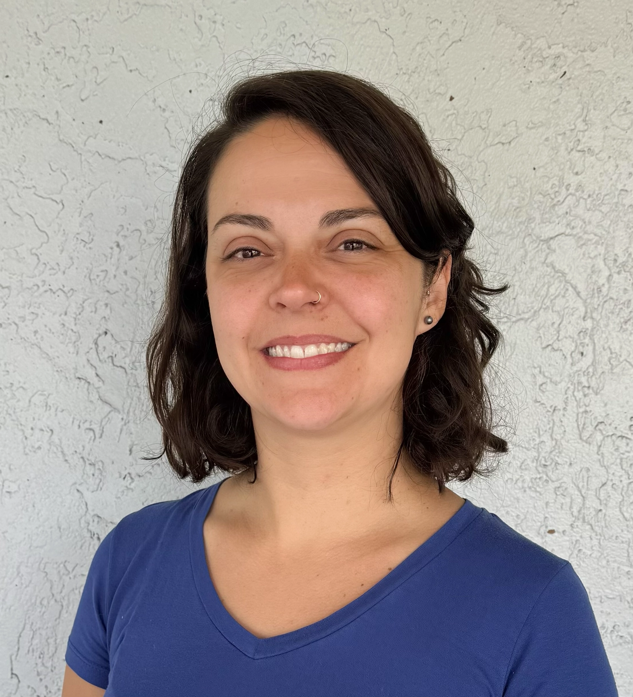 Amanda Domingues has short, dark hair, is wearing a purple top and is smiling.