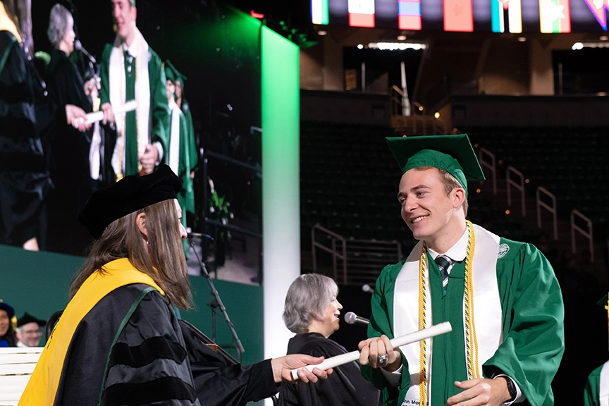 John Morrison receives his diploma from Dean Kendra Spence Chervuvelil